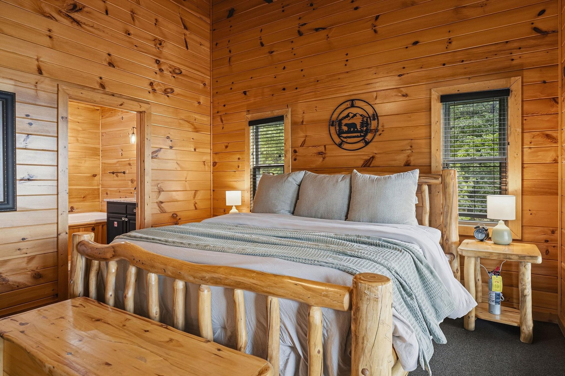 Sink into soft linens and rustic charm in your cozy bedroom, where warm wood surrounds you and natural light filters through the windows for your mountain retreat.