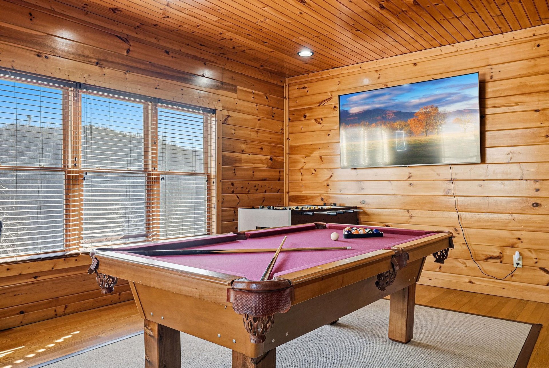 Challenge friends to a game in your cozy cabin game room, featuring warm wood walls and entertainment for hours of fun.