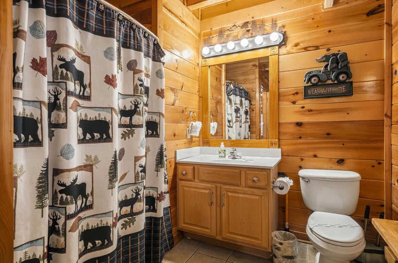 Warm wood paneling and rustic charm welcome you to this cozy cabin bathroom, complete with playful wildlife touches and everything you need to feel at home.