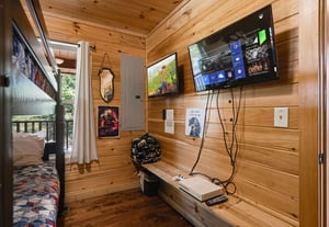 Unwind in your cozy entertainment nook with dual screens, warm wood paneling, and a gaming console ready for your downtime adventures.