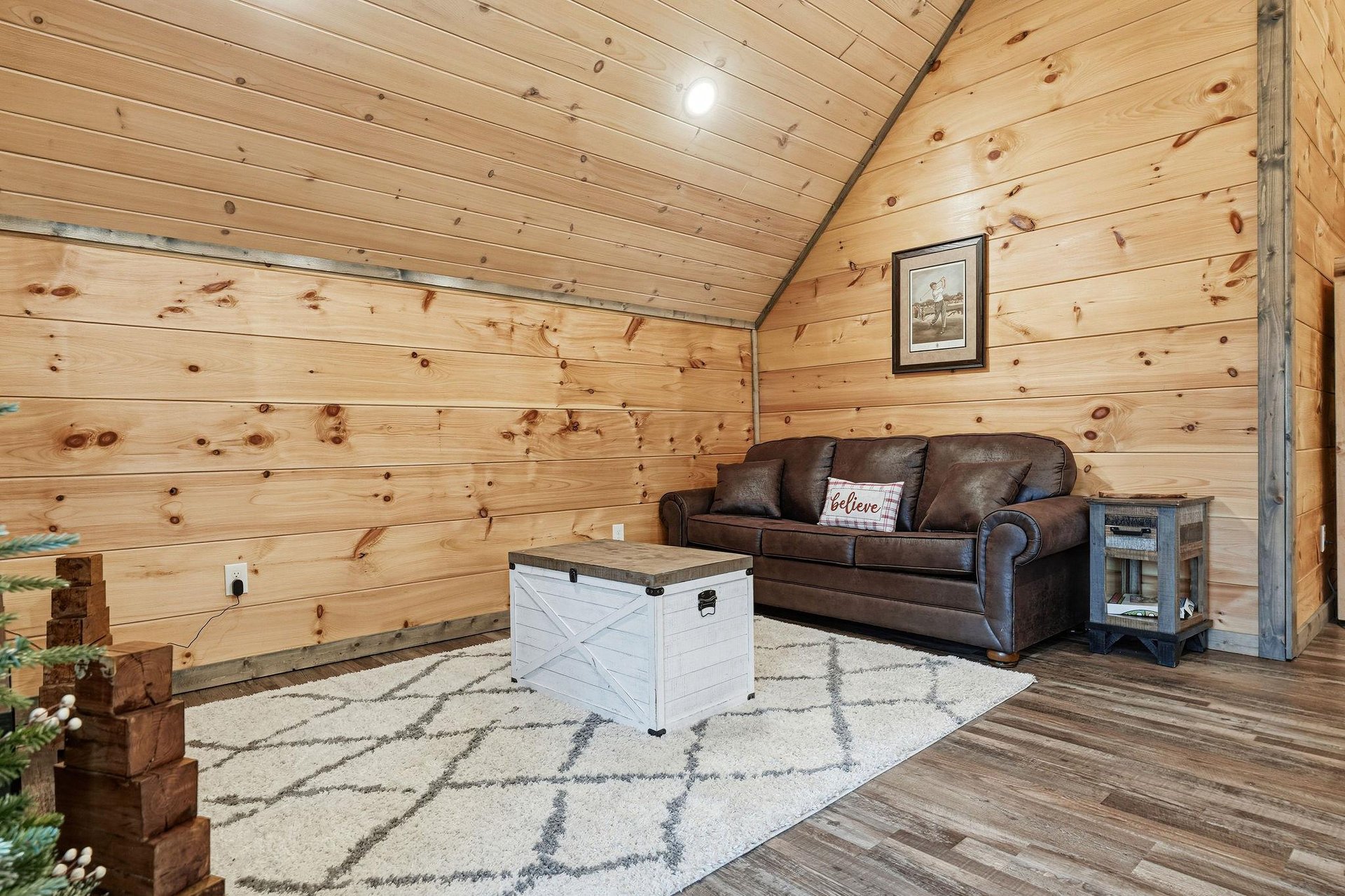 Unwind in your cozy cabin living room with warm wood walls, comfortable leather seating, and rustic charm.