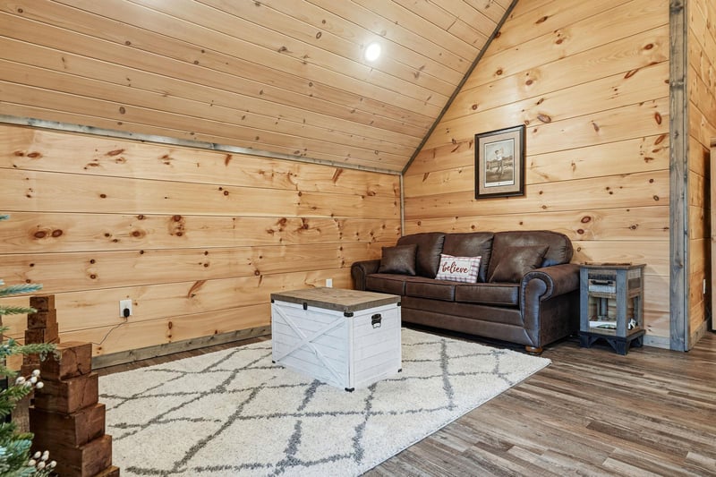 Unwind in your cozy cabin living room with warm wood walls, comfortable leather seating, and rustic charm.