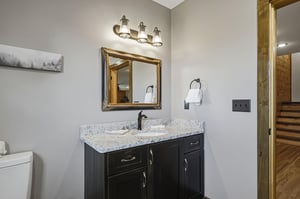 Your private bathroom features a stylish dark vanity with granite countertop, warm lighting, and fresh towels ready for you.