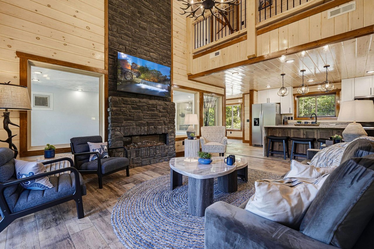 Soaring openconcept space with rustic charm and modern comfort. Plush seating by a dramatic stone fireplace and floortoceiling windows overlook the peaceful forest.