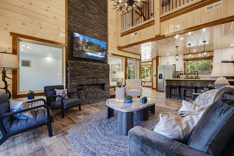 Soaring openconcept space with rustic charm and modern comfort. Plush seating by a dramatic stone fireplace and floortoceiling windows overlook the peaceful forest.