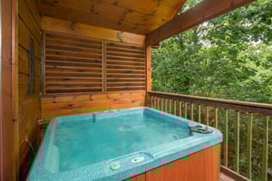 Hot tub on a covered deck at Kellys Cabin, a 1 bedroom cabin rental located in Pigeon Forge