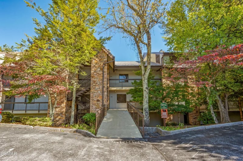 Modern multilevel building nestled among mature trees with convenient parking and accessible walkways for a comfortable arrival experience.