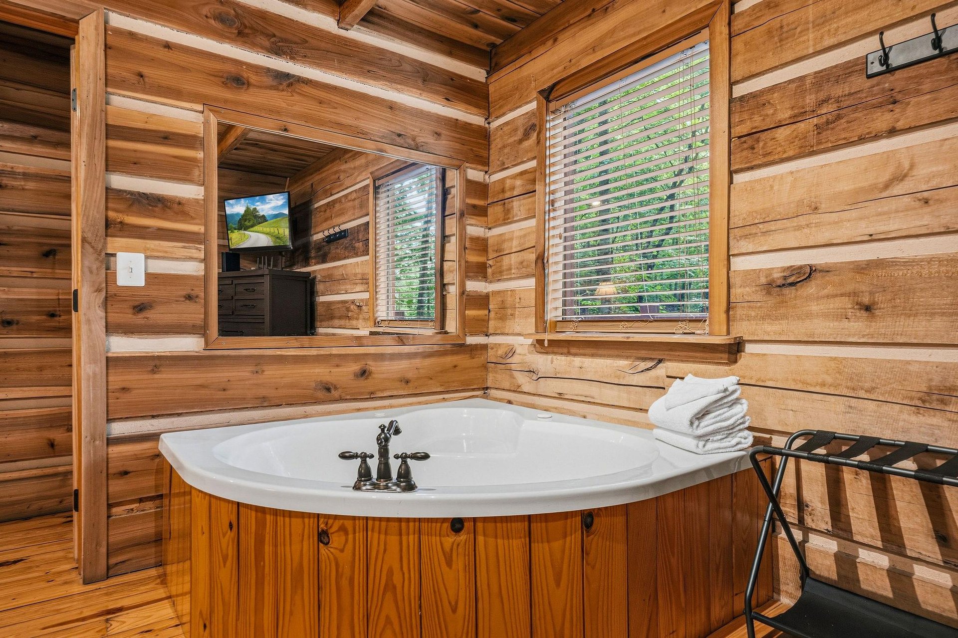 Soak your stress away in this private soaking tub surrounded by warm cedar walls, watching TV or gazing at the greenery through window blinds. Fresh towels await you on the nearby stand.