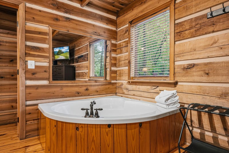Soak your stress away in this private soaking tub surrounded by warm cedar walls, watching TV or gazing at the greenery through window blinds. Fresh towels await you on the nearby stand.