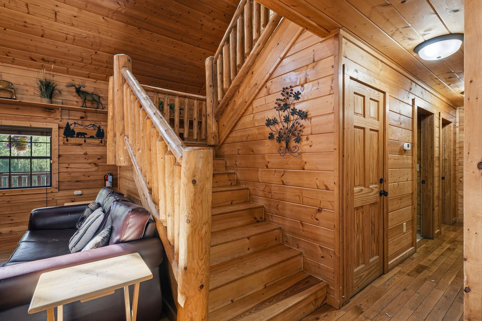 Step into your cozy log cabin where rustic charm surrounds you with warm wood walls, a comfortable leather sofa, and handcrafted staircase.
