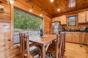 Gather around the handcrafted log table in your fully equipped kitchen, where warm wood tones and forest views create the perfect backdrop for your mountain getaway meals.