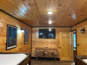 Step inside your cozy cabin retreat with warm woodpaneled walls and rustic charm. Two comfortable beds welcome you home after a day of adventure.