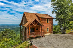 A secluded mountain cabin perched on a ridgeline, surrounded by lush forest with expansive valley views stretching to distant horizons—an idyllic retreat location.