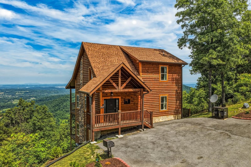 A secluded mountain cabin perched on a ridgeline, surrounded by lush forest with expansive valley views stretching to distant horizons—an idyllic retreat location.