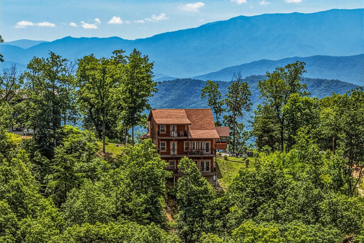 Mountain property nestled among lush greenery with stunning layered mountain ranges creating a dramatic backdrop for this elevated vacation retreat.