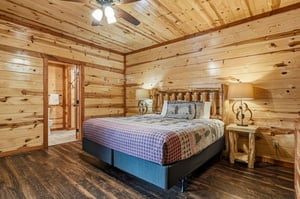 Drift off to sleep surrounded by warm knotty pine walls in this cozy cabin bedroom with rustic log headboard and handcrafted bedside tables.