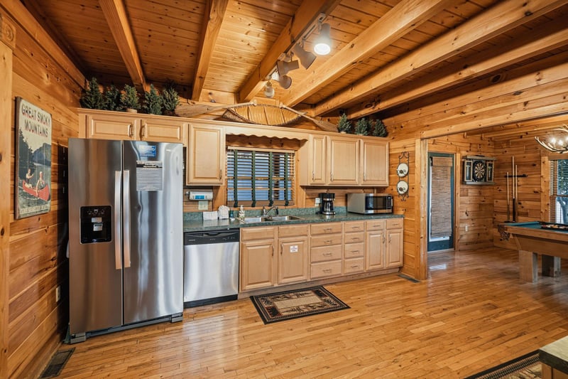 Cook your favorite meals in this fully equipped kitchen, featuring stainless steel appliances, ample counter space, and warm wood finishes that create a cozy mountain retreat atmosphere.