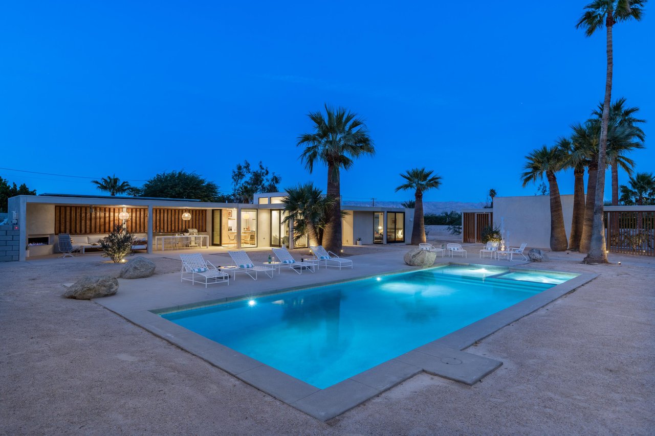 Illuminated pool, palm trees, and contemporary architecture