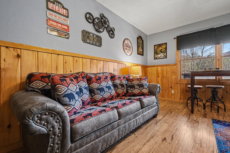 Cozy up on your plush sofa surrounded by charming cinema decor and warm wood paneling, perfect for movie nights.