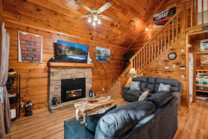 Unwind in this cozy living room featuring vaulted wood ceilings, a warm stone fireplace, and plush sectional seating—your perfect mountain retreat.