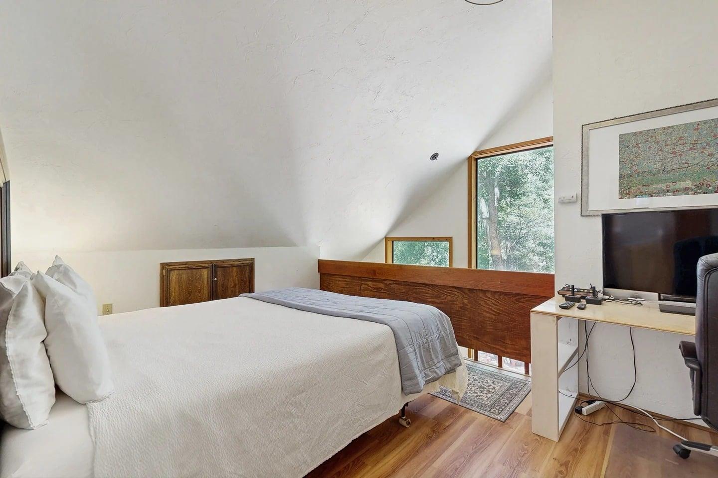 The second bedroom also features a king bed, along with its own desk and chair, a flatscreen smart TV, and a classic Atari game console for some retro fun. This bedroom shares the upstairs bathroom with the primary bedroom.