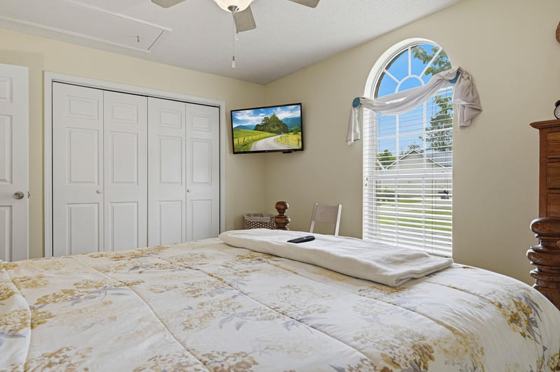 Wake up refreshed in this serene bedroom where natural light streams through elegant arched windows. Enjoy your own TV, ceiling fan, and peaceful garden views to start your day right.
