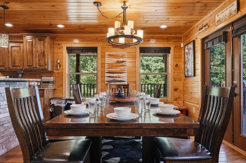 Gather around your private dining table, set for memorable meals under warm wood ceilings, with natural light streaming through windows overlooking the peaceful forest beyond.