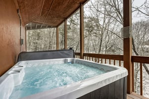 Soak in your private hot tub while winter trees create a peaceful backdrop on your covered deck.