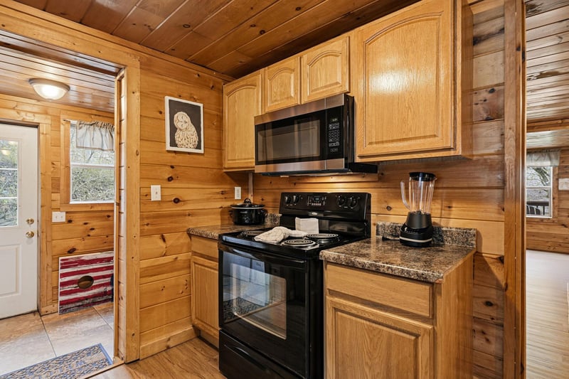 Your rustic cabin kitchen features warm wood walls, granite counters, and modern appliances for memorable mountain meals.