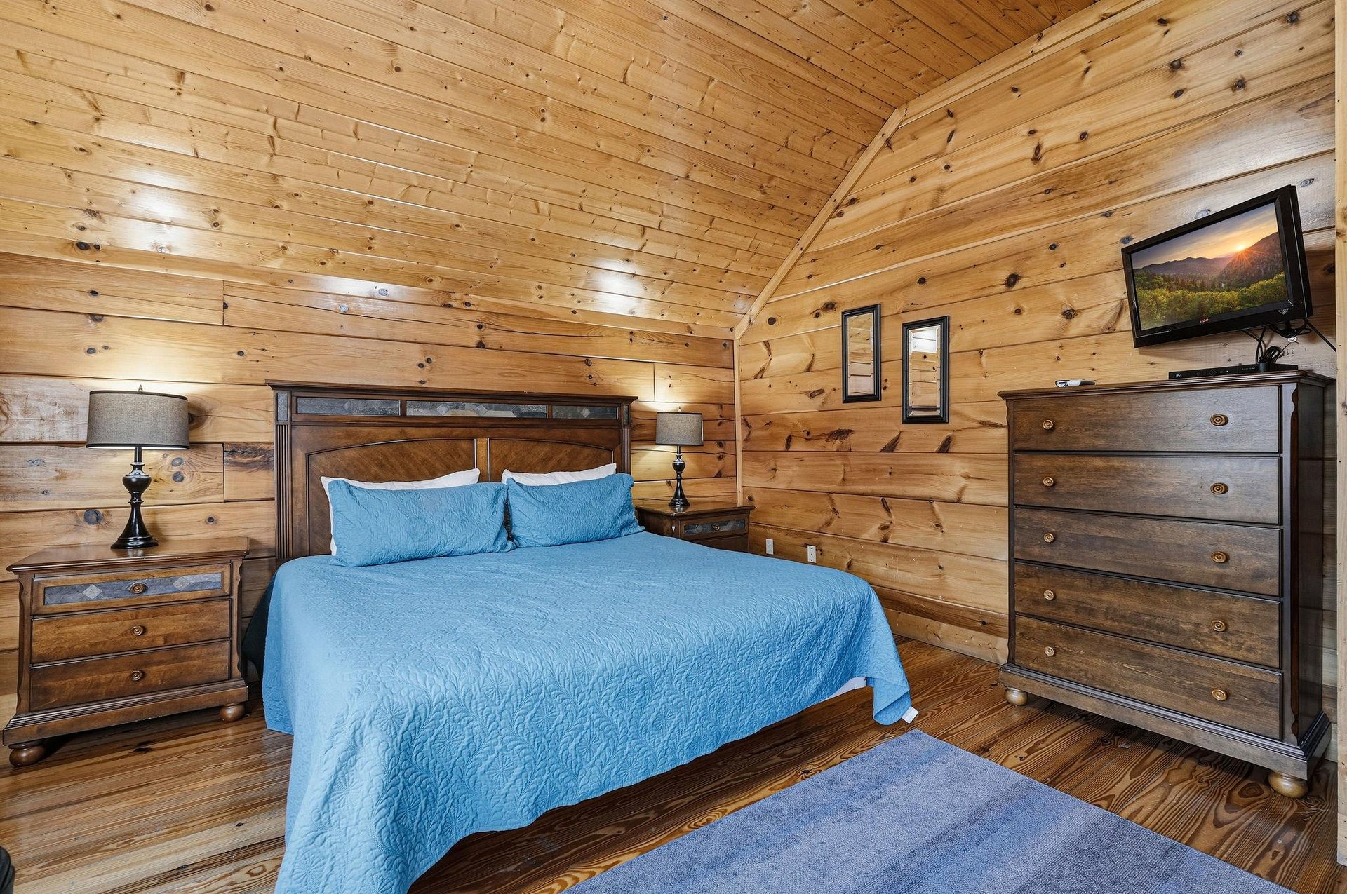 Cozy up in your rustic log cabin bedroom with warm wood walls, comfortable bedding, and modern amenities like a flatscreen TV.