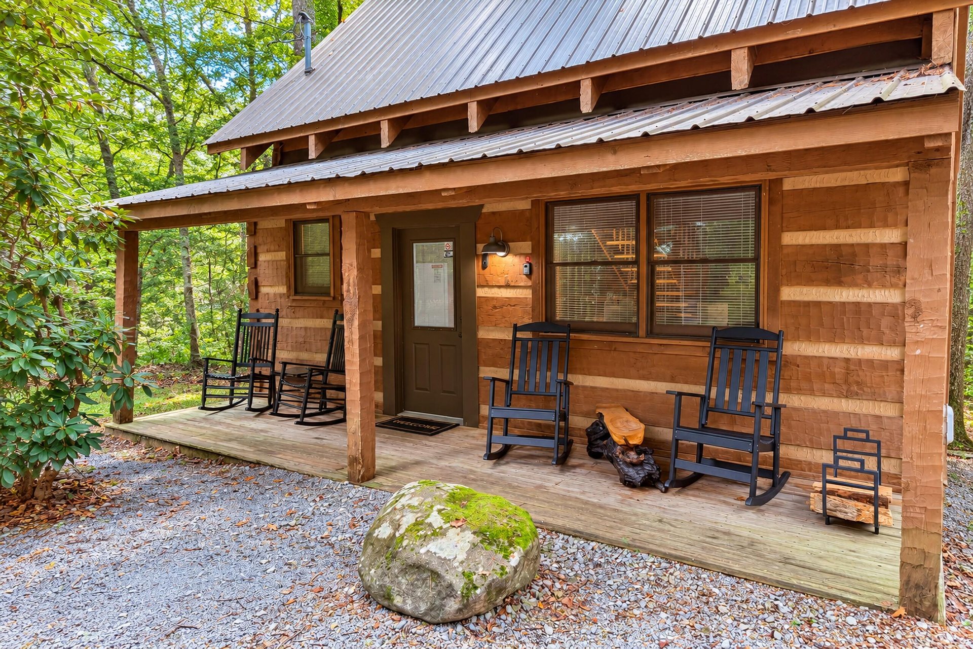 A charming wood cabin nestled in a peaceful forest setting, featuring a welcoming covered porch with classic rocking chairs for relaxing among the trees.