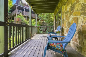 Settle into your private deck with a swing and cheerful blue chairs, surrounded by lush greenery and peaceful views of neighboring cabins tucked among the trees.