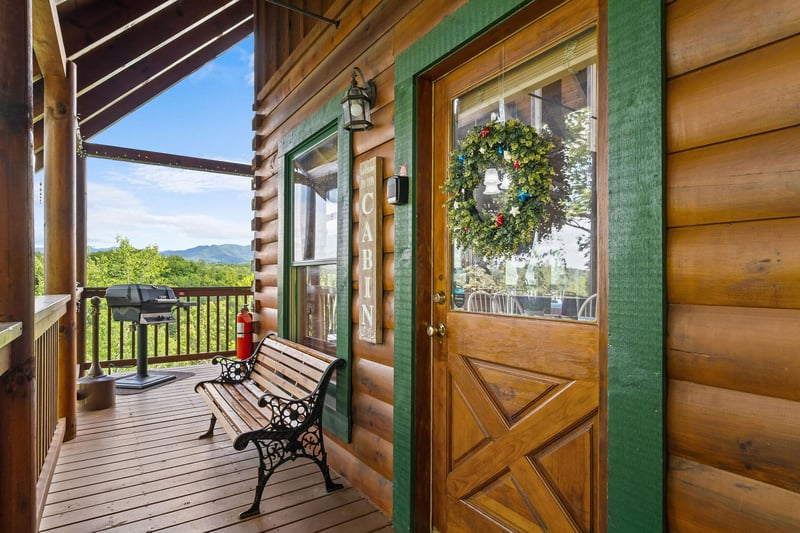 Front door of Bear Sunrise cabin with bench and grill