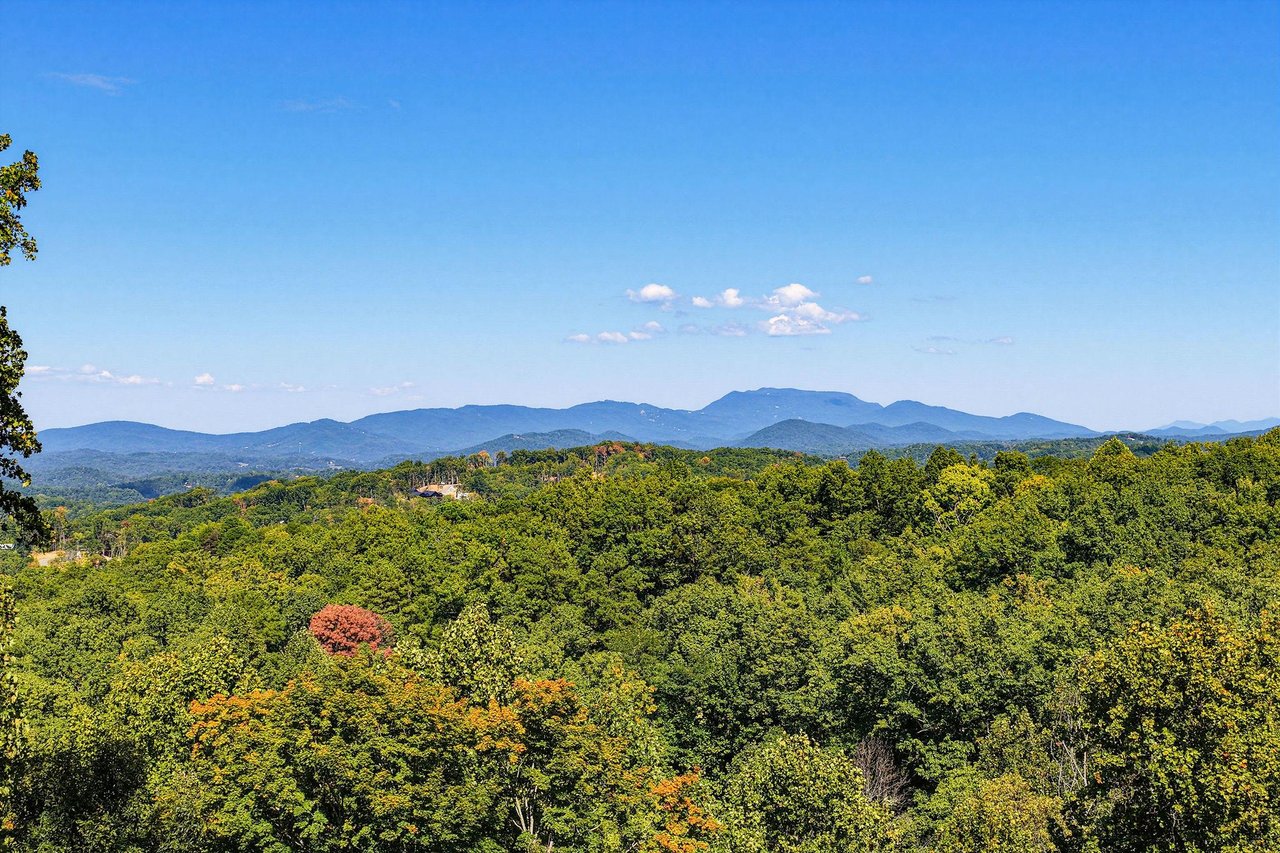 The property is set in a beautiful location with stunning mountain ranges rising above lush forests, creating a peaceful natural backdrop.