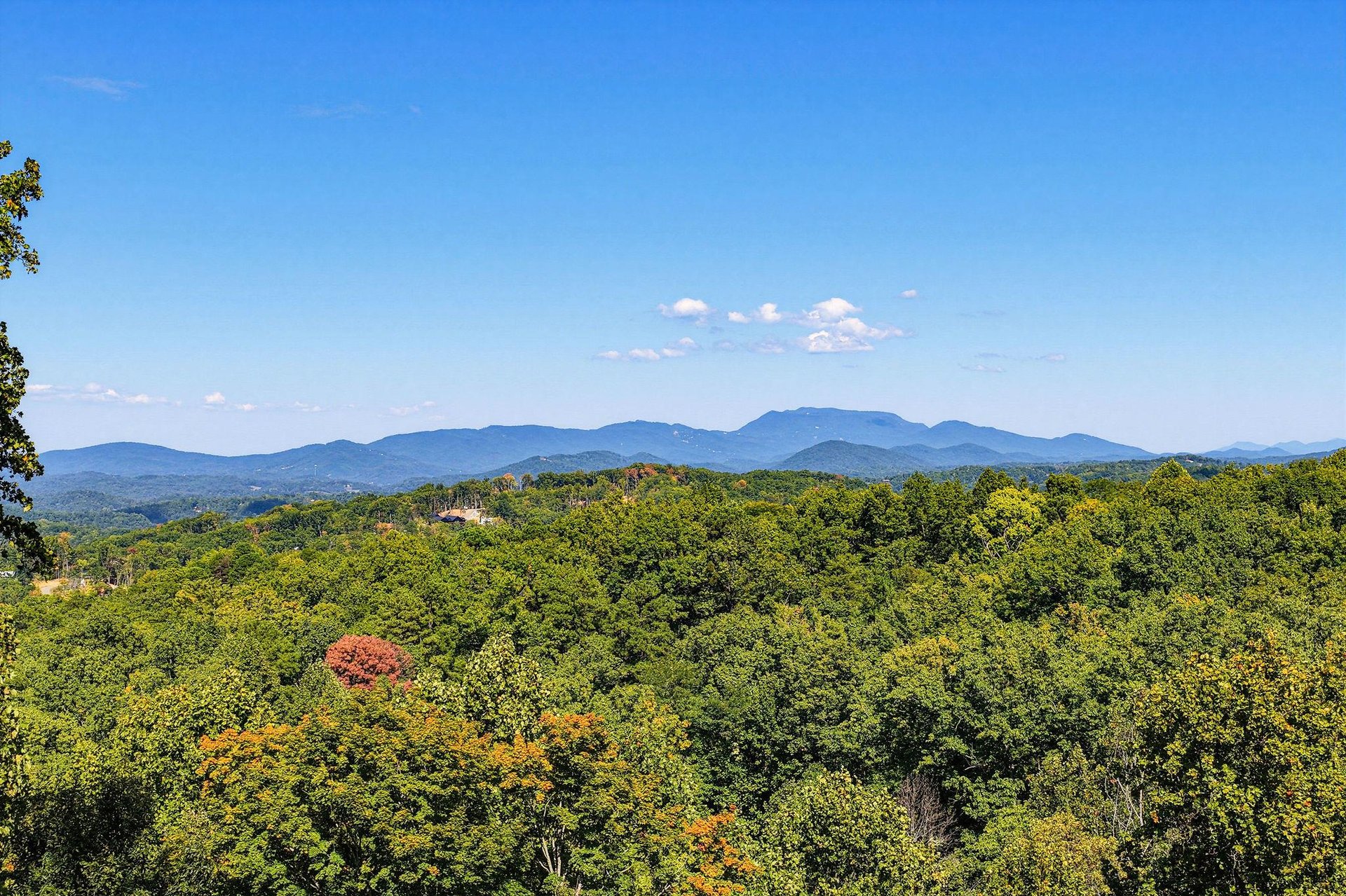 The property is set in a beautiful location with stunning mountain ranges rising above lush forests, creating a peaceful natural backdrop.