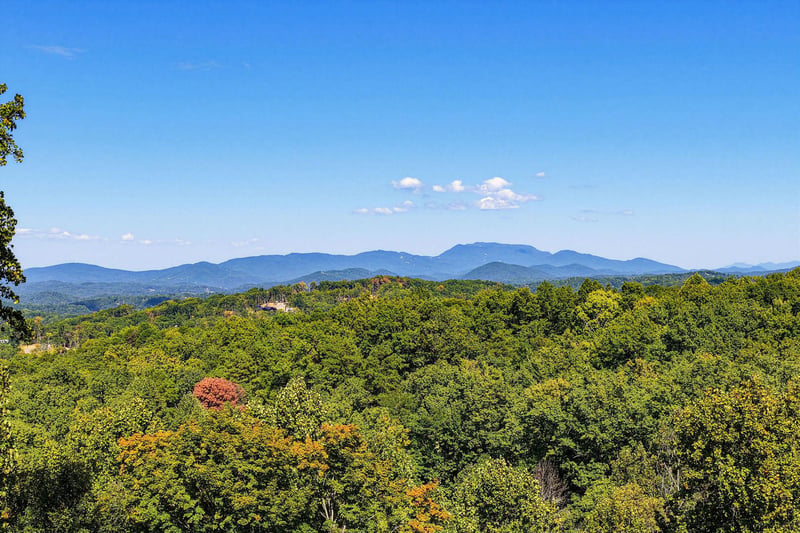 The property is set in a beautiful location with stunning mountain ranges rising above lush forests, creating a peaceful natural backdrop.