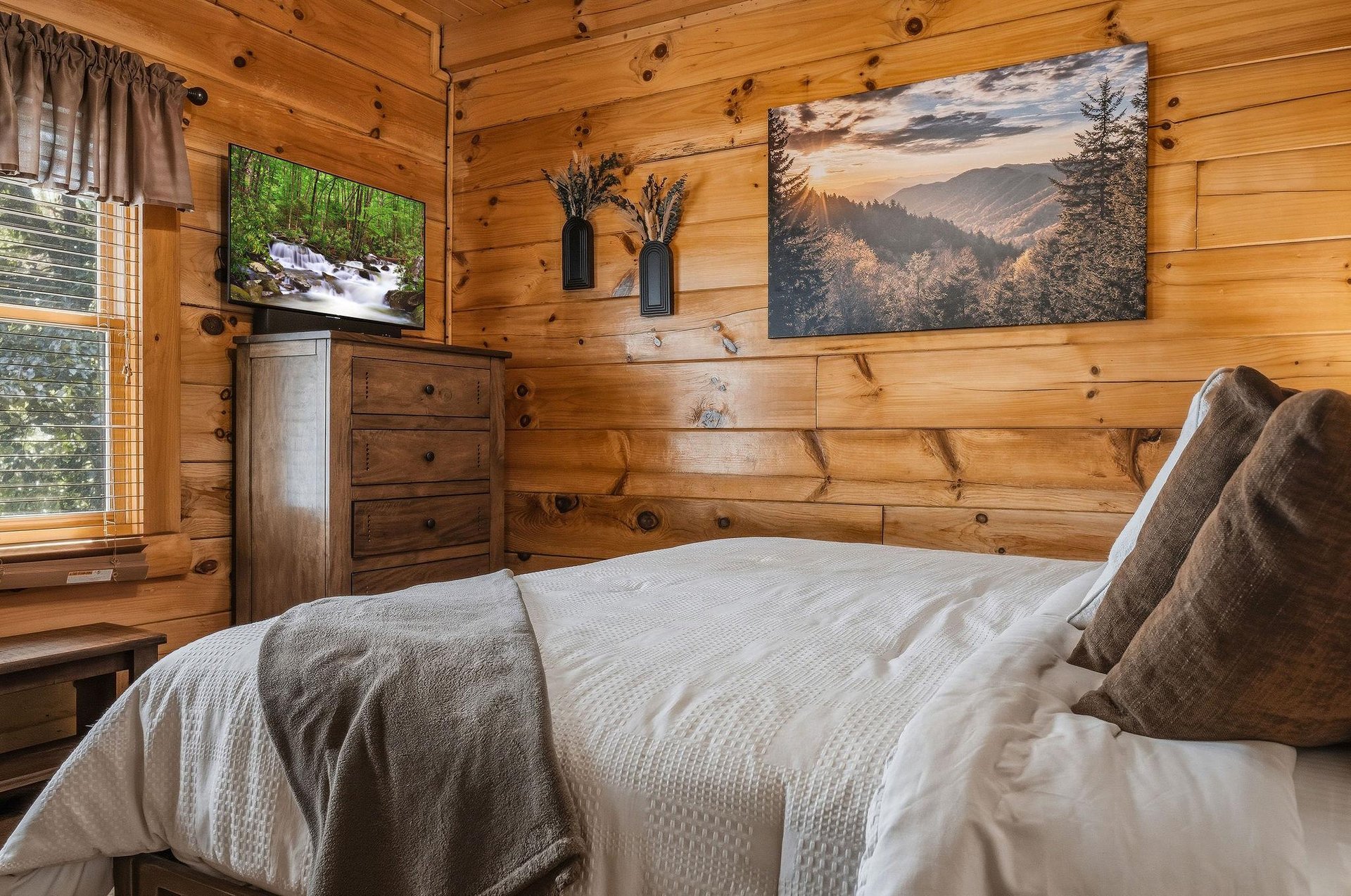 Unwind in your cozy bedroom, wrapped in rustic log walls and soft linens. Natural light pours through the window, inviting the forest inside. Let warm wood and peaceful decor ease you into a restful r
