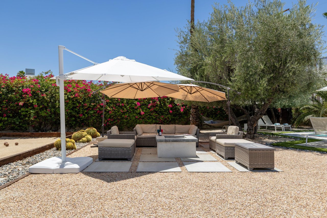 Fire pit area with plenty of outdoor seating and umbrealls for extra shade.