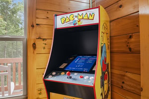 Challenge yourself to a classic game on this fullsized arcade machine, set against warm wooden walls with natural light streaming in from the nearby deck.