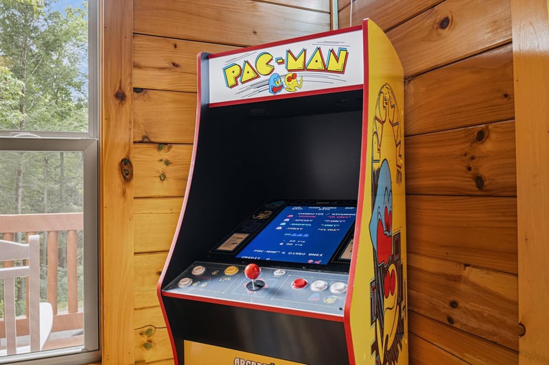 Challenge yourself to a classic game on this fullsized arcade machine, set against warm wooden walls with natural light streaming in from the nearby deck.