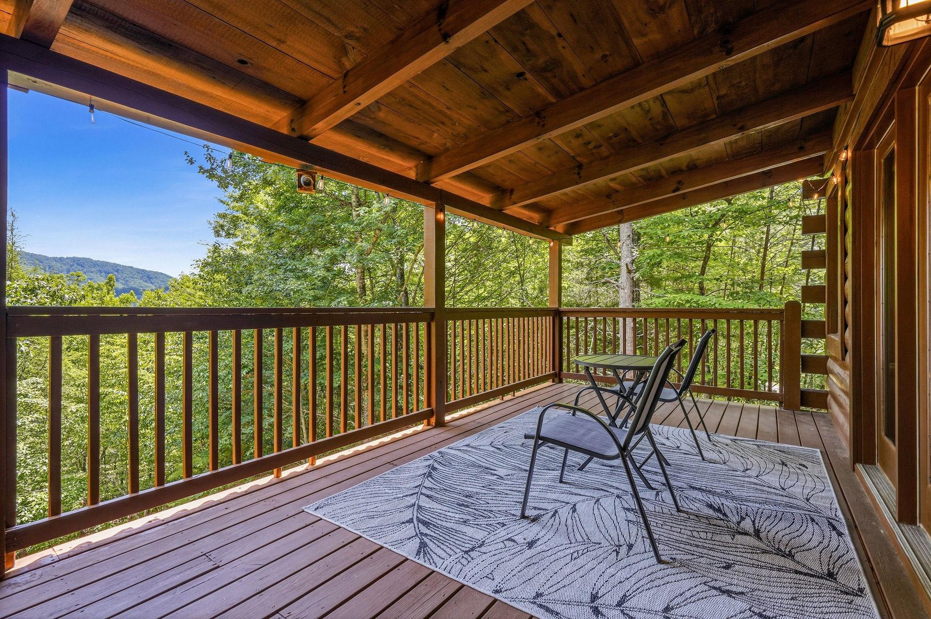 Covered deck framed by towering trees and mountain views, a tranquil spot where your morning coffee tastes even better surrounded by natures beauty.
