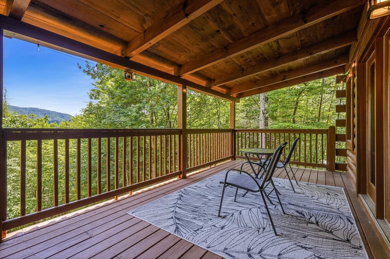 Covered deck framed by towering trees and mountain views, a tranquil spot where your morning coffee tastes even better surrounded by natures beauty.