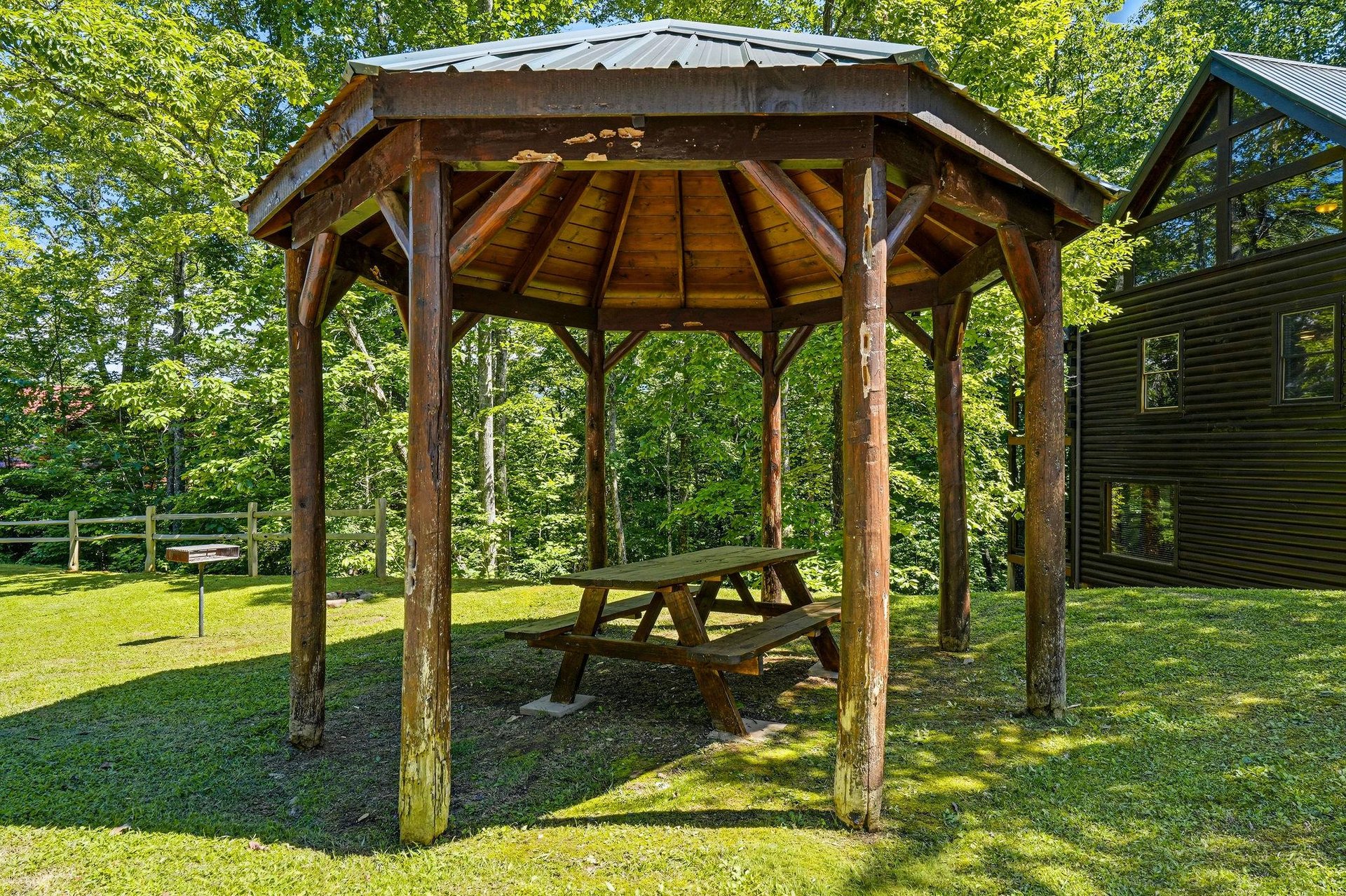 Rustic covered pavilion with picnic table nestled in lush greenery—perfect for outdoor dining, relaxing with morning coffee, or enjoying the fresh mountain air.