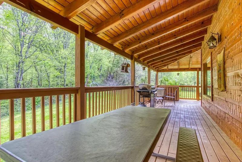 This covered deck is ready for your morning coffee or evening cookout, with a grill and seating overlooking peaceful wooded surroundings.