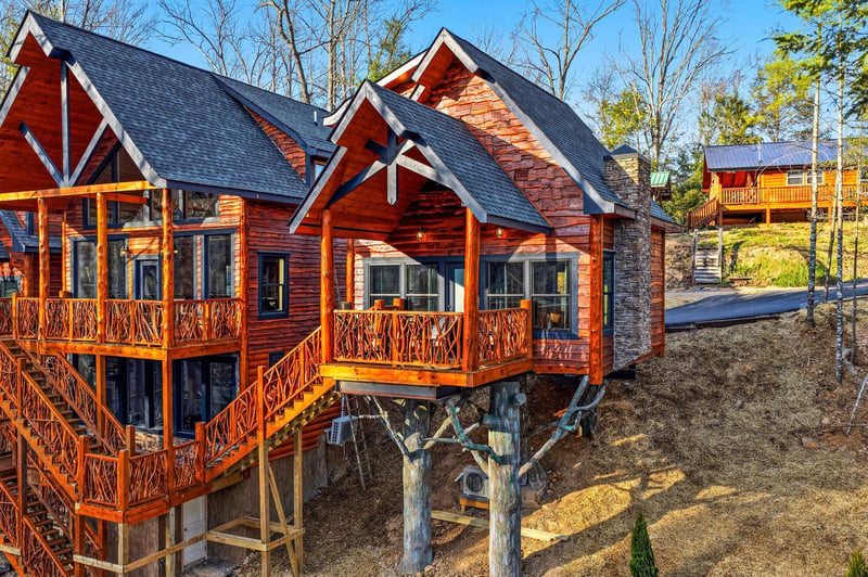 Rustic log cabin retreat elevated on stilts, surrounded by peaceful wooded grounds and neighboring mountain chalets.