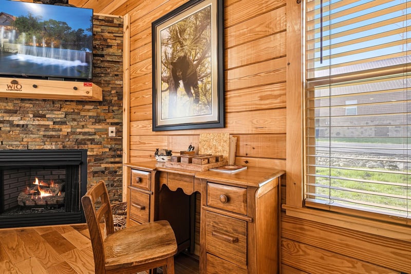 Cozy up in your rustic retreat with warm wood paneling, crackling fireplace, and charming desk nook perfect for morning coffee or evening journaling.