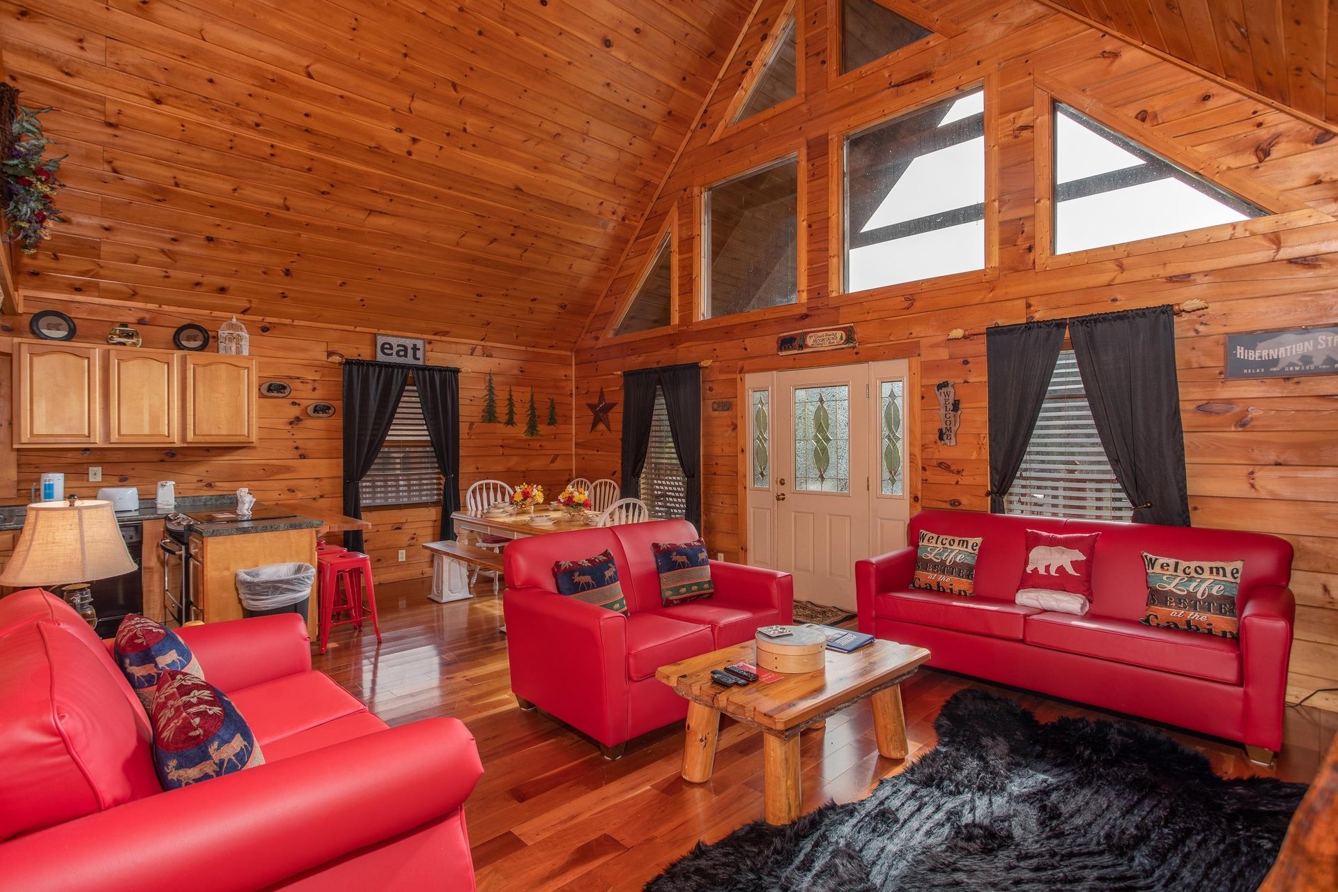 Living room with vaulted ceiling, looking into the dining room and kitchen at Hibernation Station, a 3bedroom cabin rental located in Pigeon Forge