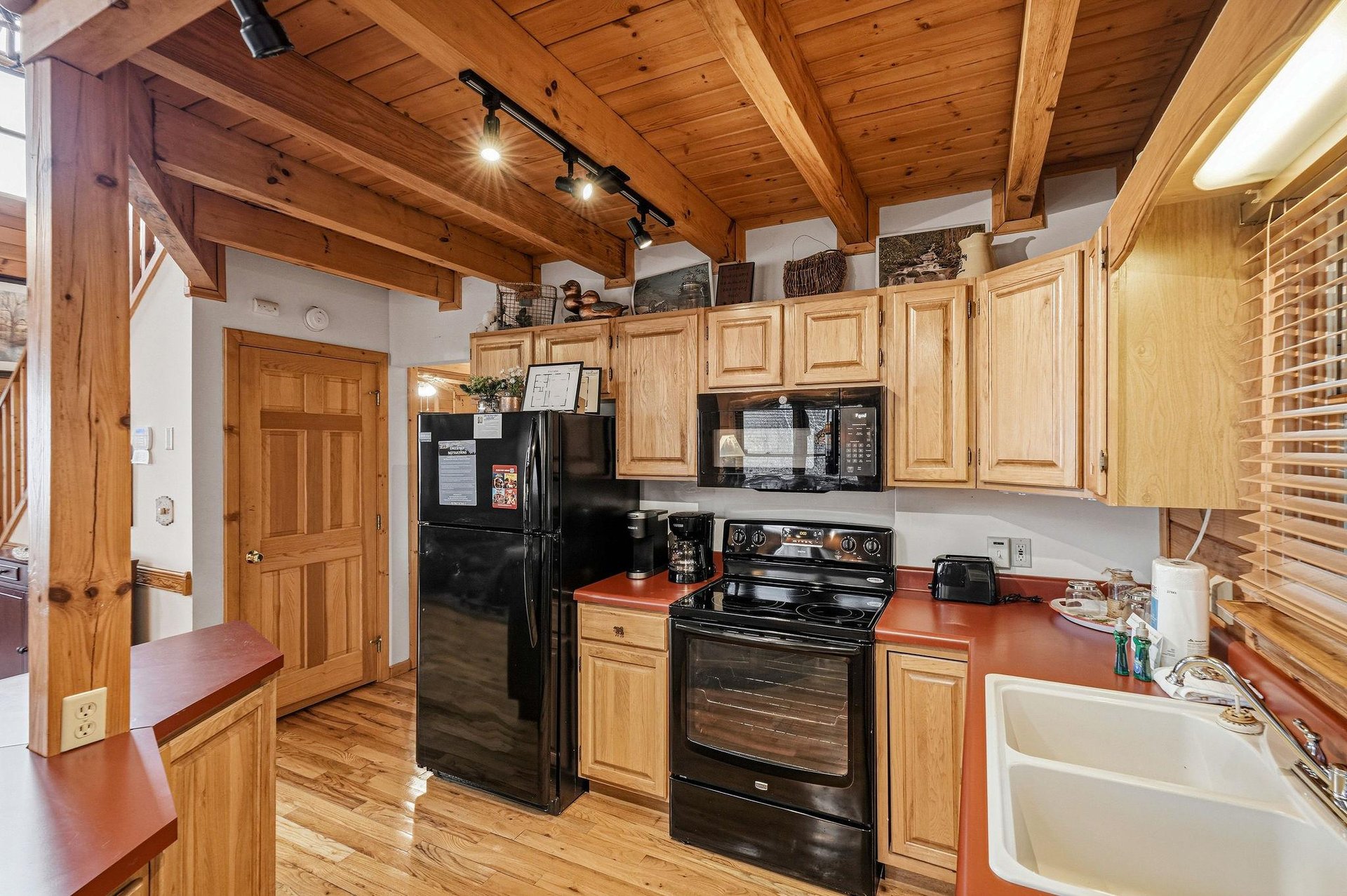 Your fully equipped kitchen awaits with warm wood details, modern appliances, and rustic charm under exposed beams.