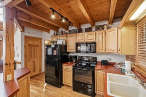 Your fully equipped kitchen awaits with warm wood details, modern appliances, and rustic charm under exposed beams.