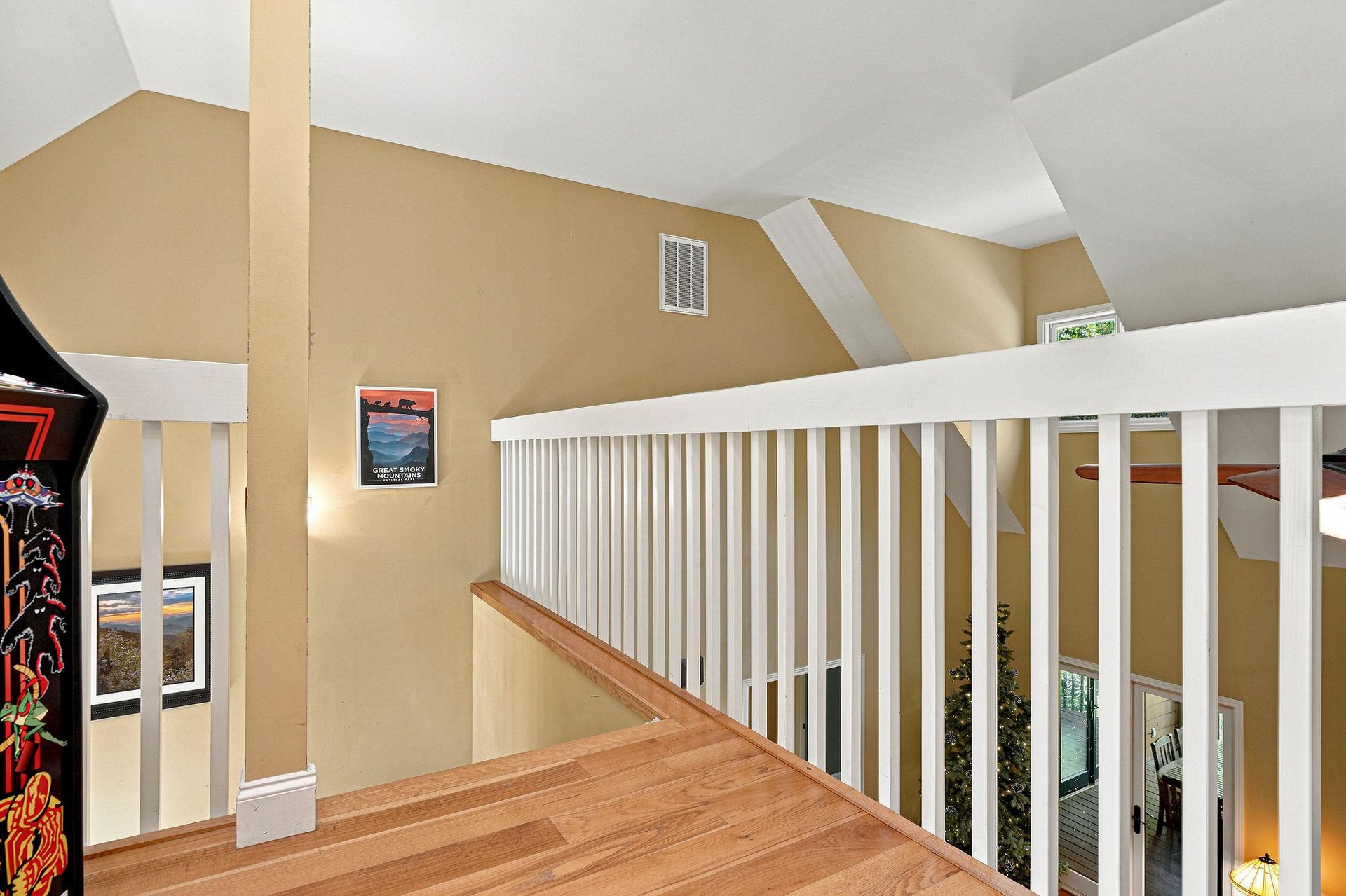 Upstairs loft space with vaulted ceilings, warm hardwood flooring, and a bright, airy atmosphere for your creative use or quiet retreat.